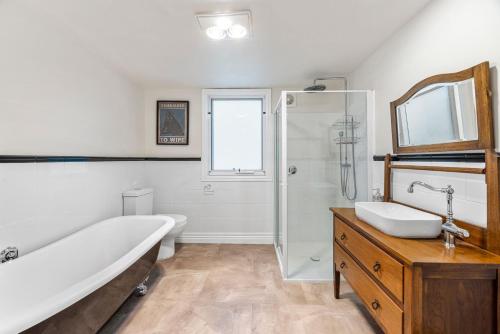 a bathroom with a tub and a shower and a sink at Jam Cottage Tolmie in Tolmie