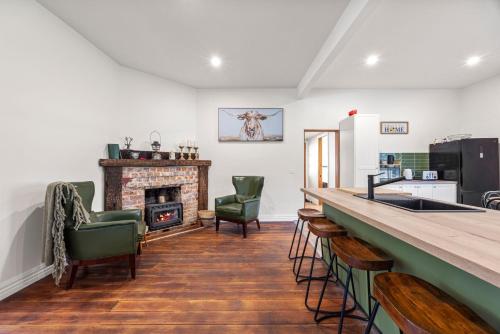 a kitchen with a counter with chairs and a fireplace at Jam Cottage Tolmie in Tolmie