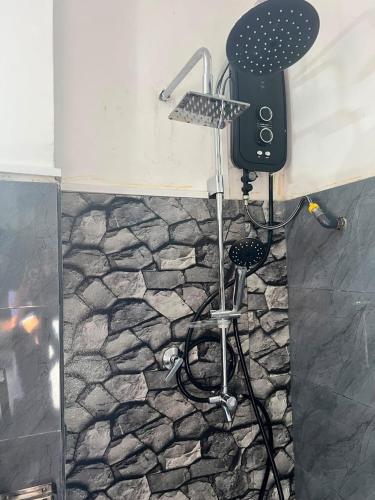 a shower in a bathroom with a stone floor at Green Mount View Cottage in Ella