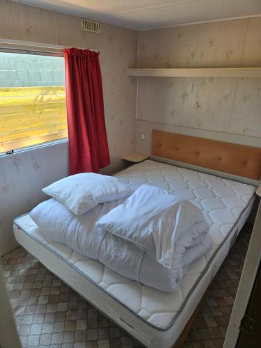 an empty bed in a room with a window at Le bungalow des champs in Saint-Georges-de-Reintembault