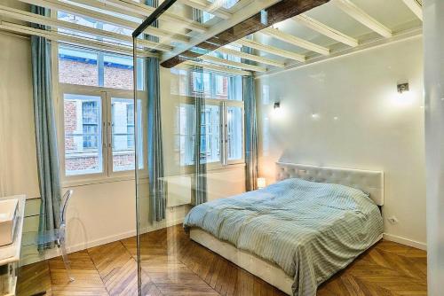 a bedroom with a bed in a room with windows at Exceptional double house with Jacuzzi in Lille