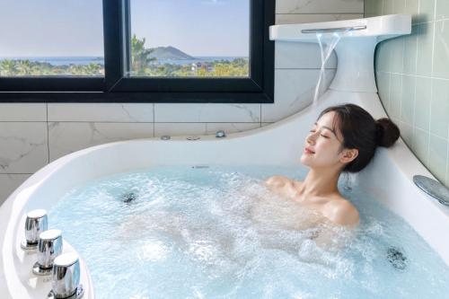 a woman is in a bath tub with a shower at Liverpool & Spa in Jeju