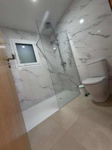 a bathroom with a toilet and a glass shower at Casa Refúgio da Natureza in Macedo de Cavaleiros
