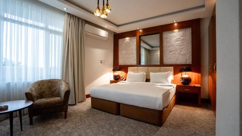 a hotel room with a bed and a chair at Shaheen Hotel Baghdad in Baghdād