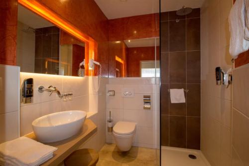a bathroom with a sink and a toilet and a shower at Hotel Munde in Telfs