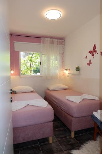 two beds in a room with a window at Apartmani Štambuk in Jelsa