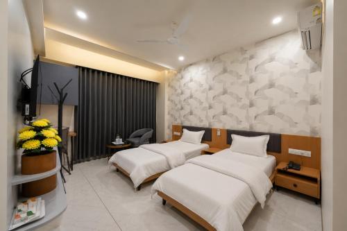 two beds in a hospital room with flowers on the wall at hotel green rio in Ahmedabad