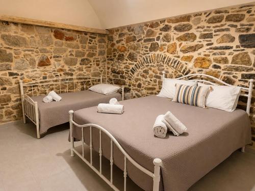 two beds in a room with a stone wall at Mastic Ev in Chios