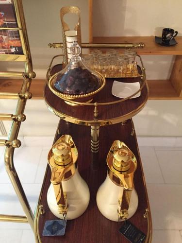 a table with gold and white shoes and a vase at Aris Furnished Apartments in Buraydah