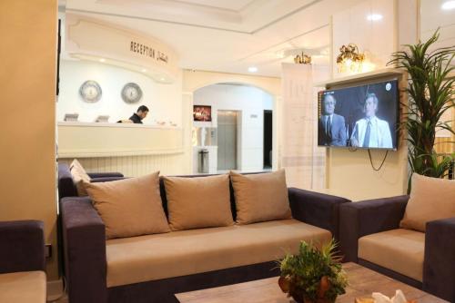 uma sala de estar com um sofá e uma televisão de ecrã plano em Aris Furnished Apartments em Buraydah