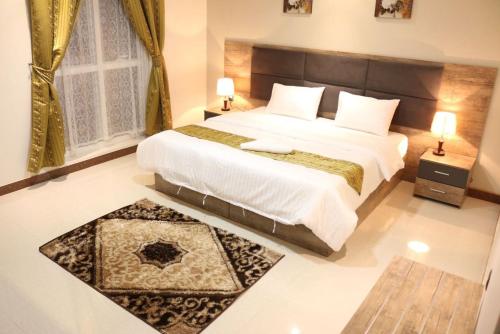 a bedroom with a large bed and a large window at Aris Furnished Apartments in Buraydah