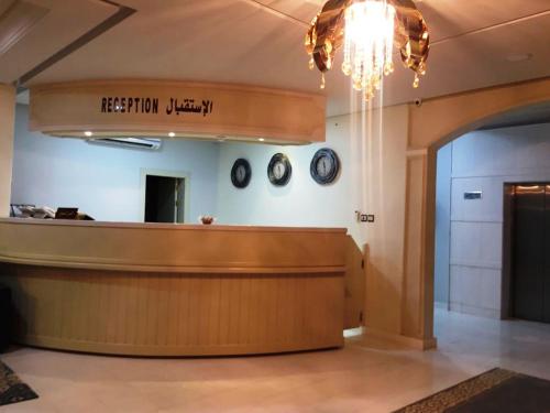 a lobby with a reception desk and clocks on the wall at Aris Furnished Apartments in Buraydah