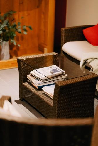 a table with a wicker chair with books on it at Das Tannberg in Lech am Arlberg