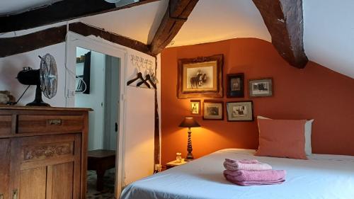 a bedroom with orange walls and a bed with towels on it at Le Manivert in Vitry-Laché