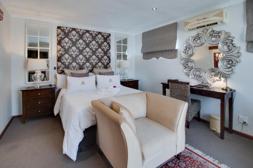 a bedroom with a bed and a chair and a mirror at Ridgeworth Boutique Guesthouse in Bellville