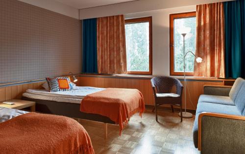ein Hotelzimmer mit einem Bett und einem Stuhl und Fenstern in der Unterkunft Aapiskukko Hotel in Pälkäne