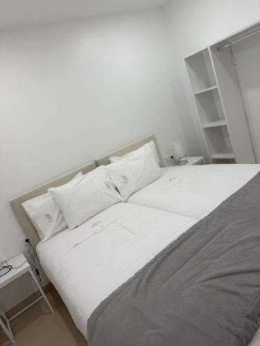 a bed with white sheets and pillows in a room at Casa do Pôr do Sol in Macedo de Cavaleiros