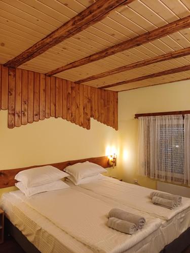 a bedroom with a large white bed with wooden ceilings at Стаи за гости "Архангел Михаил" in Kostenets