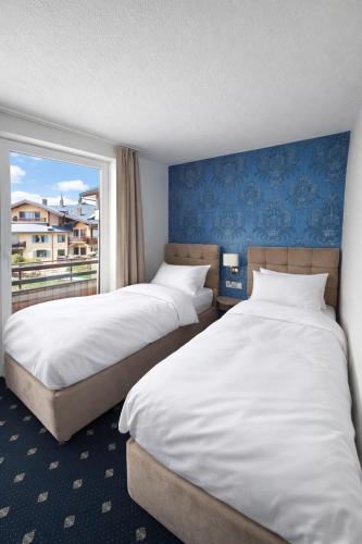 two beds in a hotel room with a window at WaldGold Aparthotel in Nagold