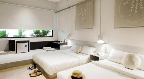 a white bedroom with two beds and a tv at Mozu Hotel SP in Kuala Lumpur