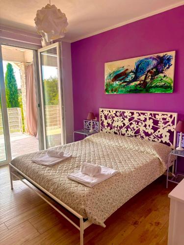 a bedroom with a bed with a purple wall at Villa Bocciolo, piscina, giardino, vasca idromassaggio in Manerba del Garda
