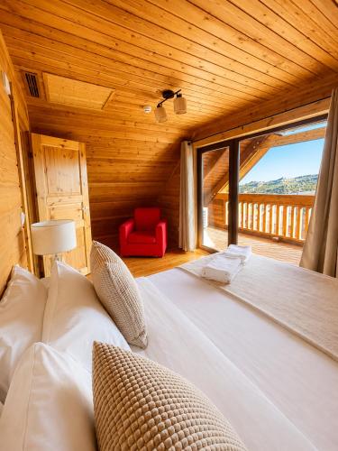 a bedroom with a large bed with a red chair at Chalet O Refúgio 2 in Penhas da Saúde