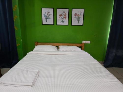 a green bedroom with a white bed with three pictures on the wall at Barza Inn in Kakkanad