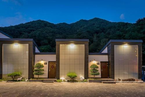 a large building with trees in front of a mountain at Hadong Cloud Hill Pension in Hadong