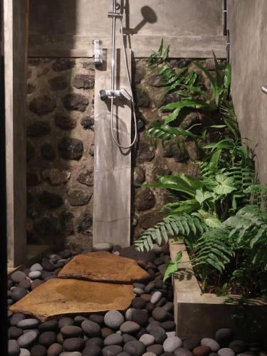 a shower in a garden with rocks and plants at Villa Hola Agung in Karangasem