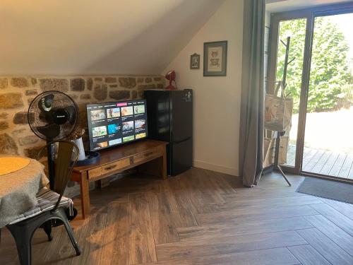 a living room with a tv and a desk with a television at Gîtes d Izel2 entre terre et mer prés d'un golf in Ploemel