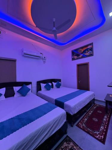 two beds in a room with purple lights at MShotel Surajgarh in Sūrajgarh