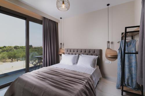 a bedroom with a bed and a large window at Athena Villas in Vasilikos