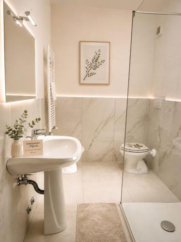 a white bathroom with a sink and a toilet at Appartamento Magnolia 325 in Pomezia
