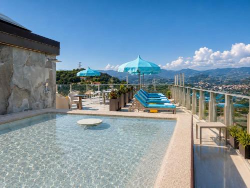 a swimming pool with chairs and umbrellas on a building at Le Stele Hotel in Lerici