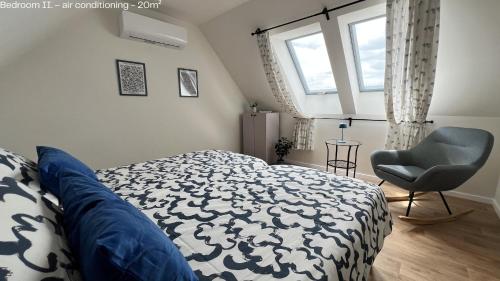 a bedroom with a bed and a chair and a window at Hello Apartman in Budaörs