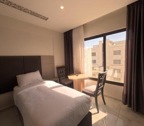 a bedroom with a bed and a desk and a window at Antalya Hotel Am in Amman
