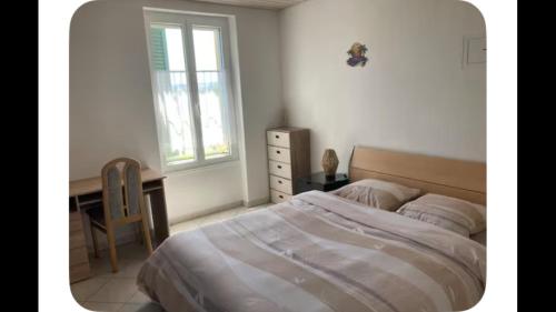a bedroom with a bed and a desk and a window at Zenitude in Goumoens-la-Ville