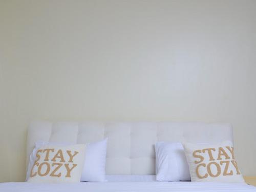a bed with white pillows with the words stay cowasy on it at Eyesha Villa in Kampala