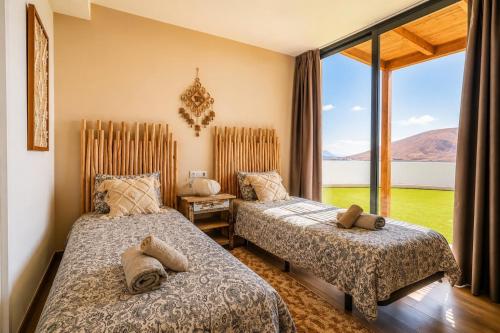 two beds in a room with a large window at Exceptional Villa With Pool in Villaverde