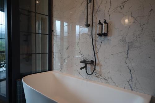 a bath tub in a bathroom with a marble wall at SaguleResort in Monasteri
