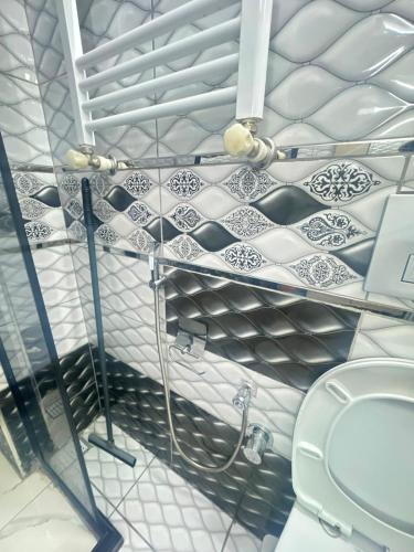 a white tiled bathroom with a toilet and a shelf at Mira Residence in Bostancı