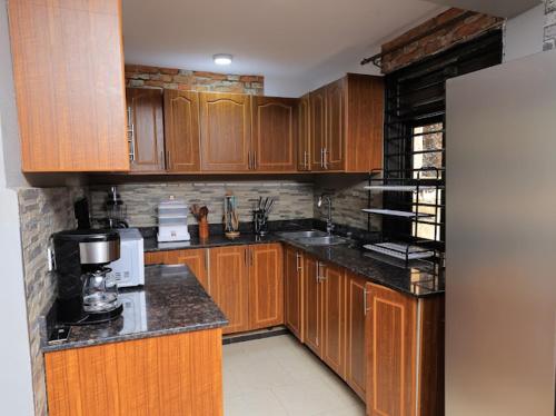 a kitchen with wooden cabinets and a refrigerator at Eyesha Villa in Kampala