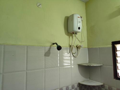 a bathroom with a soap dispenser on the wall at RR Home Stay in Karaikal