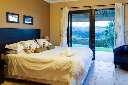 a bedroom with a large bed and a large window at Drakensberg Vultures View in Cathkin Park