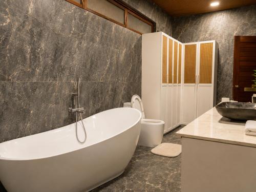 a bathroom with a tub and a toilet and a sink at Sunset Villas Palauig Zambales in Palauig