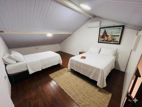 a attic bedroom with two beds and a rug at Residência Ilha Bela - Casa Inteira no Centro Histórico de São Luís in São Luís