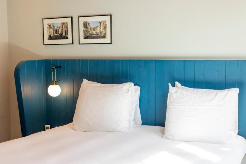 a bed with white pillows and a blue head board at Cozy Pillow in Utrecht