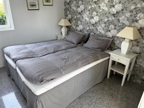 ein Bett in einem Schlafzimmer mit Nachttisch und einem Tisch mit Lampe in der Unterkunft Kullsbacka in Skanör med Falsterbo