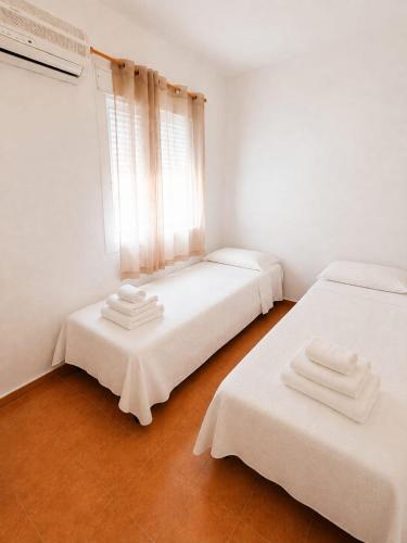 two beds in a white room with a window at Apartamento Chicago in Mazagón