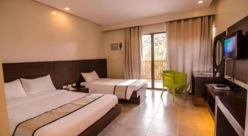 a hotel room with two beds and a television at Apple Tree Resort & Hotel in Opol